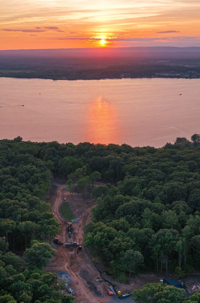 An overhead drone image with a dramatic sunset over Saratoga lake, with the construction progress of Phyllian's Bluff in the foreground.